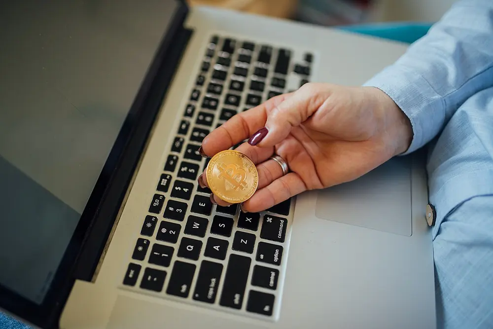Physical bitcoin coin held in a hand - soccer betting with crypto